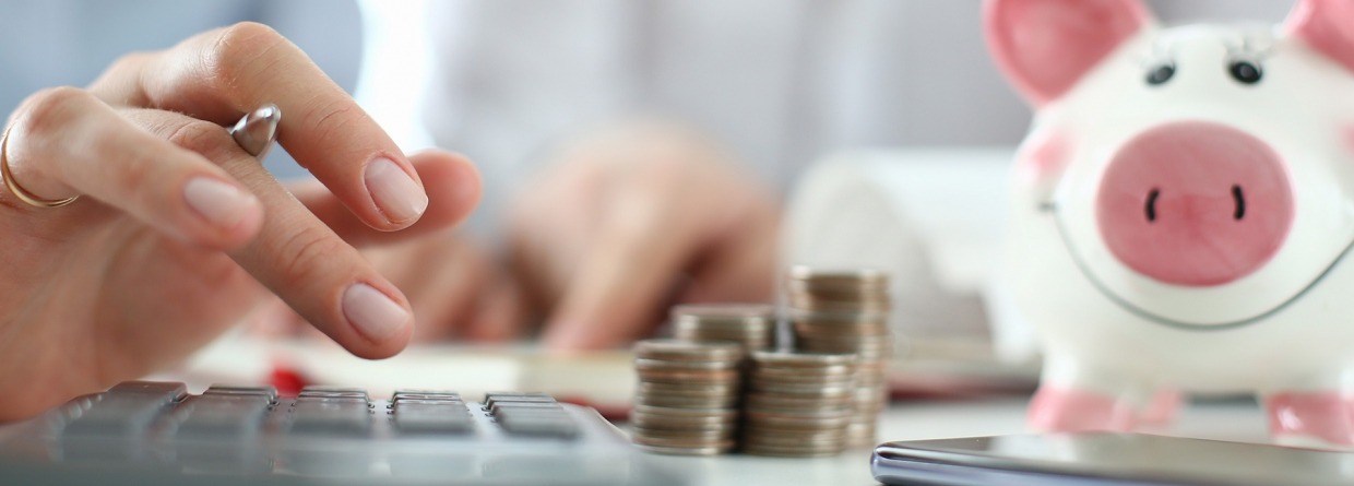 man en vrouw aan tafel met rekenmachine, geld en spaarvarken